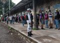 Migrantes haciendo fila vigilados por una agente de la Guardia Nacional